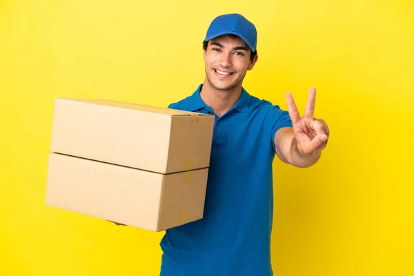 Delivery Man Isolated Yellow Wall Smiling Showing Victory Sign — Stockfoto