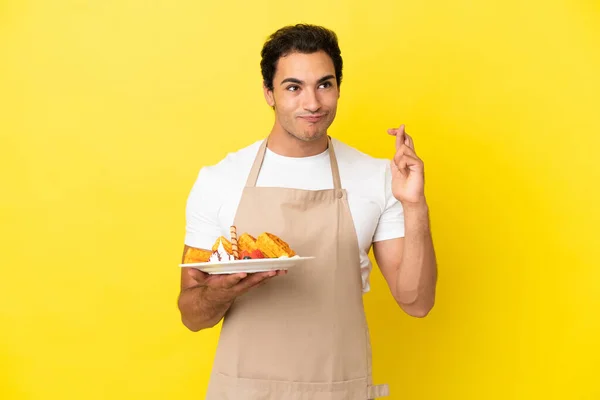 Restaurant Waiter Holding Waffles Isolated Yellow Background Fingers Crossing Wishing — Stockfoto