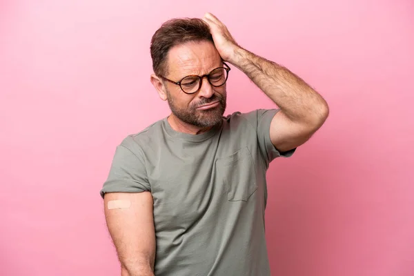 Middle age man wearing a band aids isolated on pink background having doubts and with confuse face expression