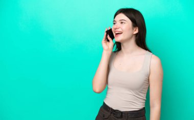 Young Russian woman isolated on green background keeping a conversation with the mobile phone