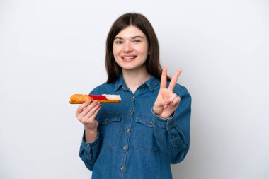 Beyaz arka planda saşimi tutan genç Rus kadın gülümsüyor ve zafer işareti gösteriyor.