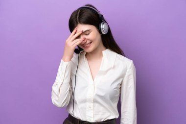 Mor arka planda izole edilmiş kulaklıkla çalışan pazarlamacı Rus kadın kahkahalar atıyor.