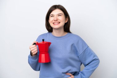 Beyaz arka planda izole edilmiş kahve fincanı tutan genç Rus kadın kolları kalçasında ve gülümsüyor.