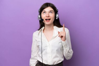 Mor arka planda izole edilmiş bir kulaklıkla çalışan pazarlamacı Rus kadın yukarı bakıyor ve şaşırıyor.