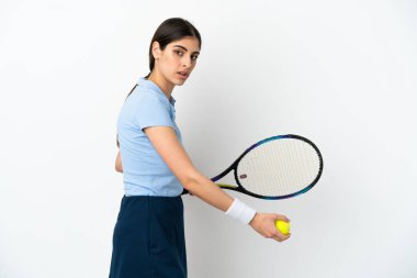 Beyaz arka planda tenis oynayan beyaz tenli genç kadın.