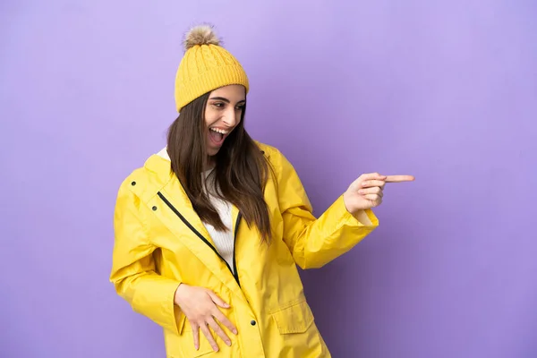 Young Caucasian Woman Wearing Rainproof Coat Isolated Purple Background Pointing —  Fotos de Stock