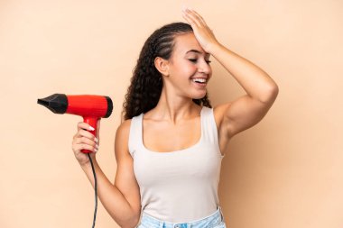 Bej arka planda izole edilmiş saç kurutma makinesini tutan genç bir kadın bir şeyin farkına vardı ve çözüme niyetlendi.