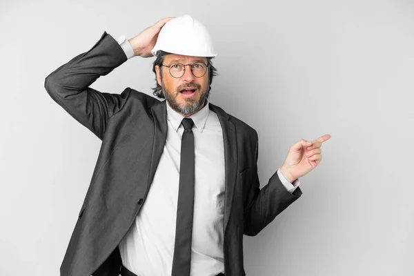 Young Architect Man Helmet Isolated Background Surprised Pointing Finger Side — Φωτογραφία Αρχείου
