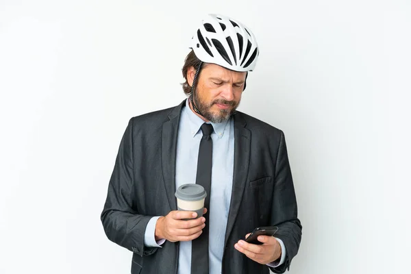 Business senior man with a bike helmet isolated on white background holding coffee to take away and a mobile