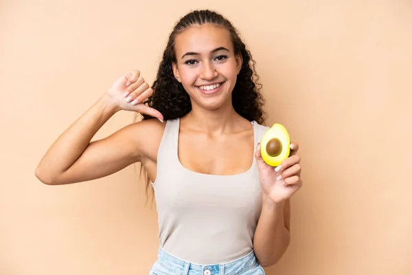 Young Woman Holding Avocado Isolated Beige Background Proud Self Satisfied — Fotografia de Stock