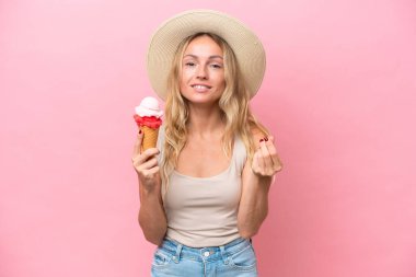 Pembe arka planda izole edilmiş dondurma tutan genç Rus kadın para hareketi yapıyor.