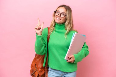 Pembe arka planda izole edilmiş genç bir bayan en iyinin işareti olarak parmağını kaldırıyor.