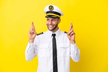 Kafkasyalı pilot sarı arka planda izole edilmiş ve şans diliyor.