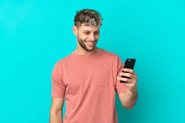 Young handsome caucasian man isolated on blue background making a selfie