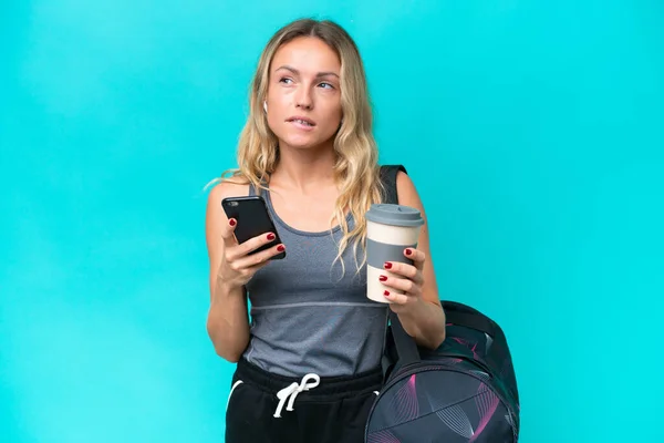 Junge Sportlerin Mit Sporttasche Isoliert Auf Blauem Hintergrund Mit Kaffee — Stockfoto