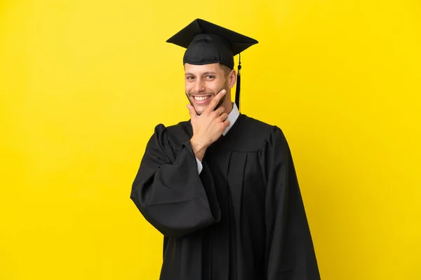 Junger Universitätsabsolvent Kaukasischer Mann Isoliert Auf Gelbem Hintergrund Lächelnd — Stockfoto