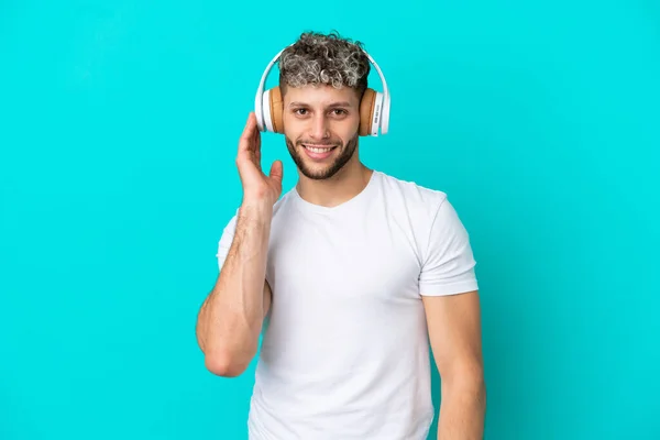 Joven Guapo Caucásico Aislado Sobre Fondo Azul Escuchando Música — Foto de Stock