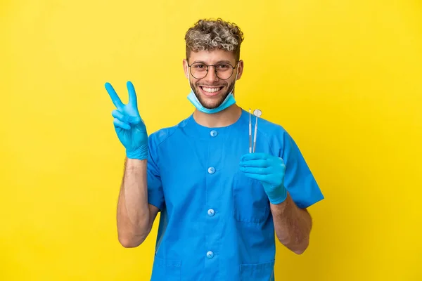 Dentysta Biały Mężczyzna Trzyma Narzędzia Izolowane Żółtym Tle Uśmiechając Się — Zdjęcie stockowe