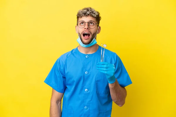 Dentysta Kaukaski Mężczyzna Trzyma Narzędzia Izolowane Żółtym Tle Patrząc Górę — Zdjęcie stockowe