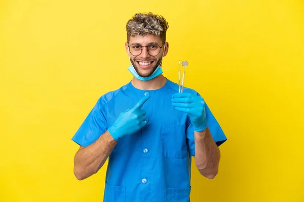 Homem Dentista Caucasiano Segurando Ferramentas Isoladas Fundo Amarelo Apontando Para — Fotografia de Stock