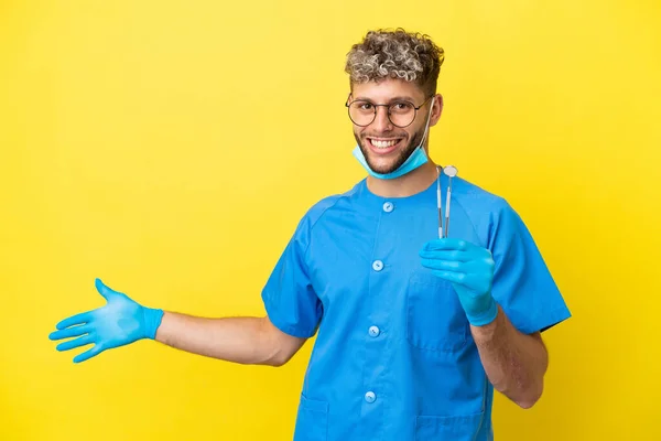 Dentista Caucasiano Homem Segurando Ferramentas Isoladas Fundo Amarelo Estendendo Mãos — Fotografia de Stock