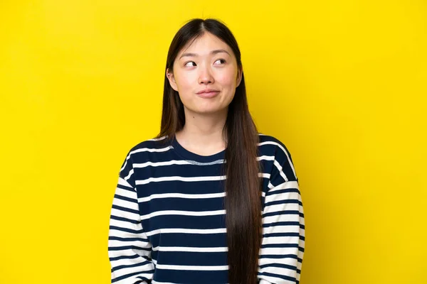 Young Chinese Woman Isolated Yellow Background Having Doubts While Looking — Foto Stock