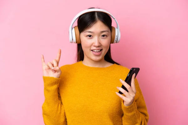 Giovane Donna Cinese Isolata Sfondo Rosa Ascoltando Musica Con Gesto — Foto Stock