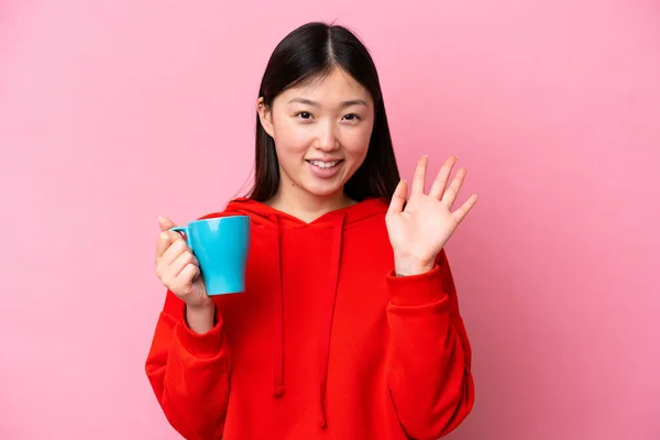 Young Chinese Woman Holding Cup Coffee Isolated Pink Background Saluting — Φωτογραφία Αρχείου