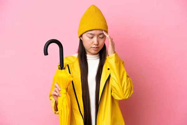 Young Chinese Woman Rainproof Coat Umbrella Isolated Pink Background Headache —  Fotos de Stock