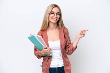 Güzel sarışın kız öğrenci beyaz arka planda izole edilmiş, parmağını yana doğru gösteriyor.