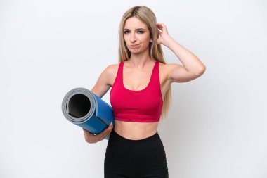 Genç sarışın kadın yoga derslerine giderken beyaz arka planda izole edilmiş bir minder tutuyor. Şüpheleri var.