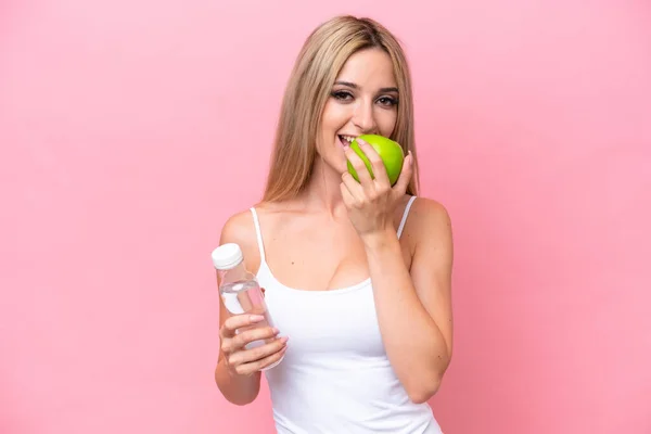 Pretty Blonde Woman Isolated Pink Background Bottle Water Eating Apple — Stockfoto