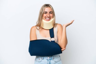 Kırık kollu ve askı takan bir kadın beyaz arka planda izole edilmiş, davet edilmesi için ellerini yana uzatıyor.