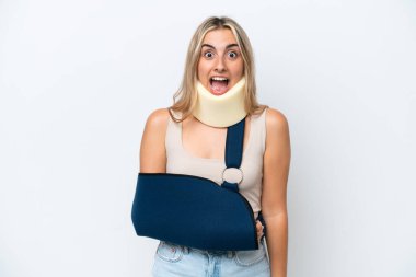 Kırık kollu ve askı takan bir kadın beyaz arka planda, şaşırmış yüz ifadesi ile izole edilmiş.