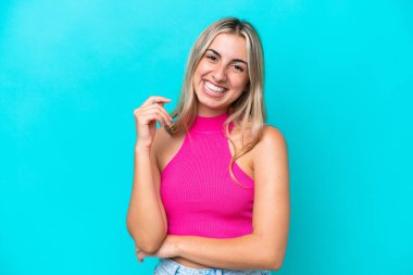 Mavi arka planda izole edilmiş genç beyaz kadın gülüyor.