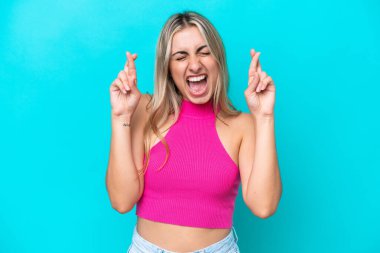 Genç beyaz kadın, mavi arka planda izole edilmiş ve şans diliyor.