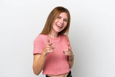 Beyaz arka planda izole edilmiş genç bir İngiliz kadın şaşırmış ve ön tarafı işaret ediyor.