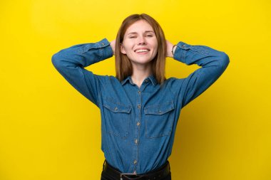Sarı arka planda yalnız yaşayan genç İngiliz kadın gülüyor.
