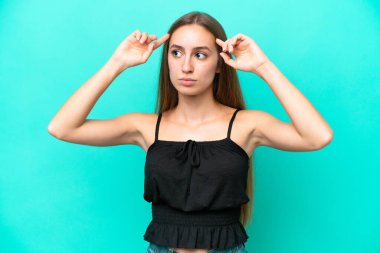 Kafkasyalı genç bir kadın mavi arka planda izole edilmiş. Şüpheleri ve düşünceleri var.