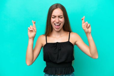 Genç beyaz kadın, mavi arka planda izole edilmiş ve şans diliyor.