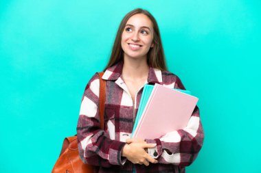 Kafkas kökenli genç bir kadın mavi arka planda izole edilmiş, yukarı bakarken bir fikir düşünüyor.