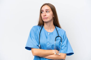 Beyaz arka planda aşırı izole genç hemşire omuzlarını kaldırırken şüpheyle hareket ediyor.