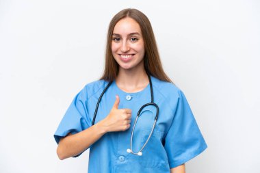 Beyaz arka planda izole edilmiş genç bir hemşire baş parmak hareketi yapıyor.