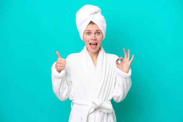 Young Woman Bathrobe Isolated Blue Background Showing Sign Thumb Gesture — Stockfoto