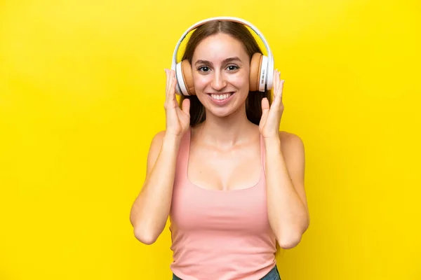 若いですCaucasian女性隔離上の黄色の背景リスニング音楽 — ストック写真