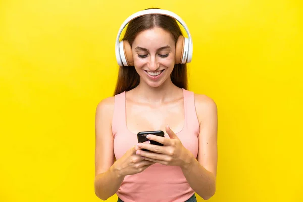 Giovane Donna Caucasica Isolata Sfondo Giallo Ascoltando Musica Guardando Cellulare — Foto Stock