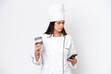 Genç Brezilyalı aşçı kadın beyaz arka planda izole edilmiş. Elinde kahve ve cep telefonu var.