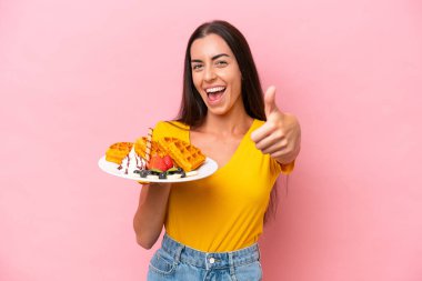 Pembe arka planda güzel bir şey olduğu için gözleme tutan beyaz bir kadın var.