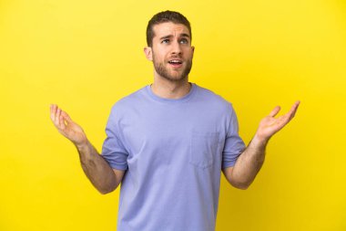 Sarışın yakışıklı adam izole edilmiş sarı arka planda baskı altında.