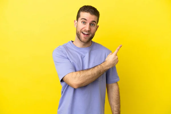 Handsome Blonde Man Isolated Yellow Background Surprised Pointing Side — Stockfoto